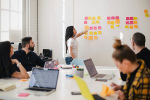 Group of employees in a meeting, collaborating and discussing ideas around a table in a modern office setting