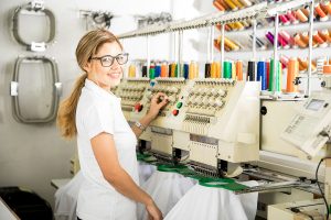 Contract embroidery technician working on bulk garment order using industrial embroidery machine