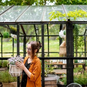 Woman in a bright glass extension surrounded by indoor plants.
