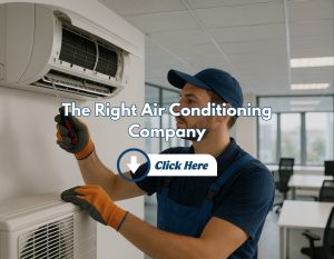 A professional technician in blue overalls and gloves working on an air conditioning unit in an office setting, representing expert service for selecting the right air conditioning company.