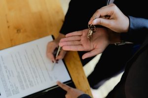 person signing documents and being handed house keys
