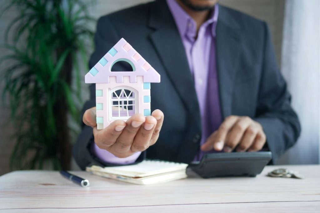 Cardiff mortgage broker holding a model house while reviewing mortgage calculations and property financing options.